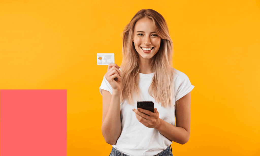 woman holding a credit card and a phone and smiling.